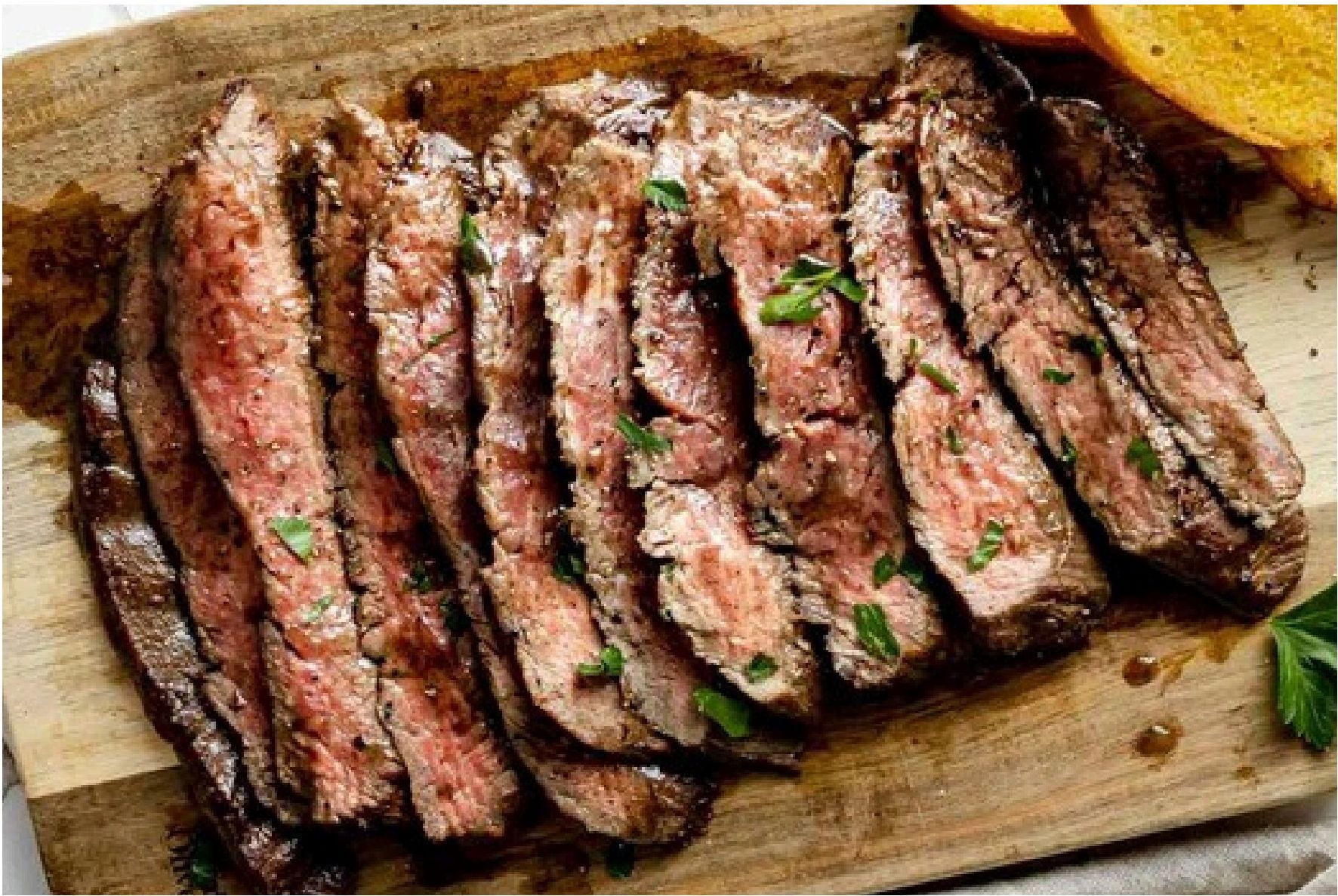 Sliced flank steak on a wooden board