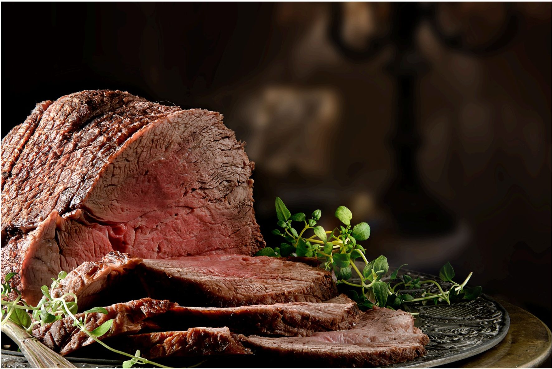 Sliced roast beef on a platter with herbs